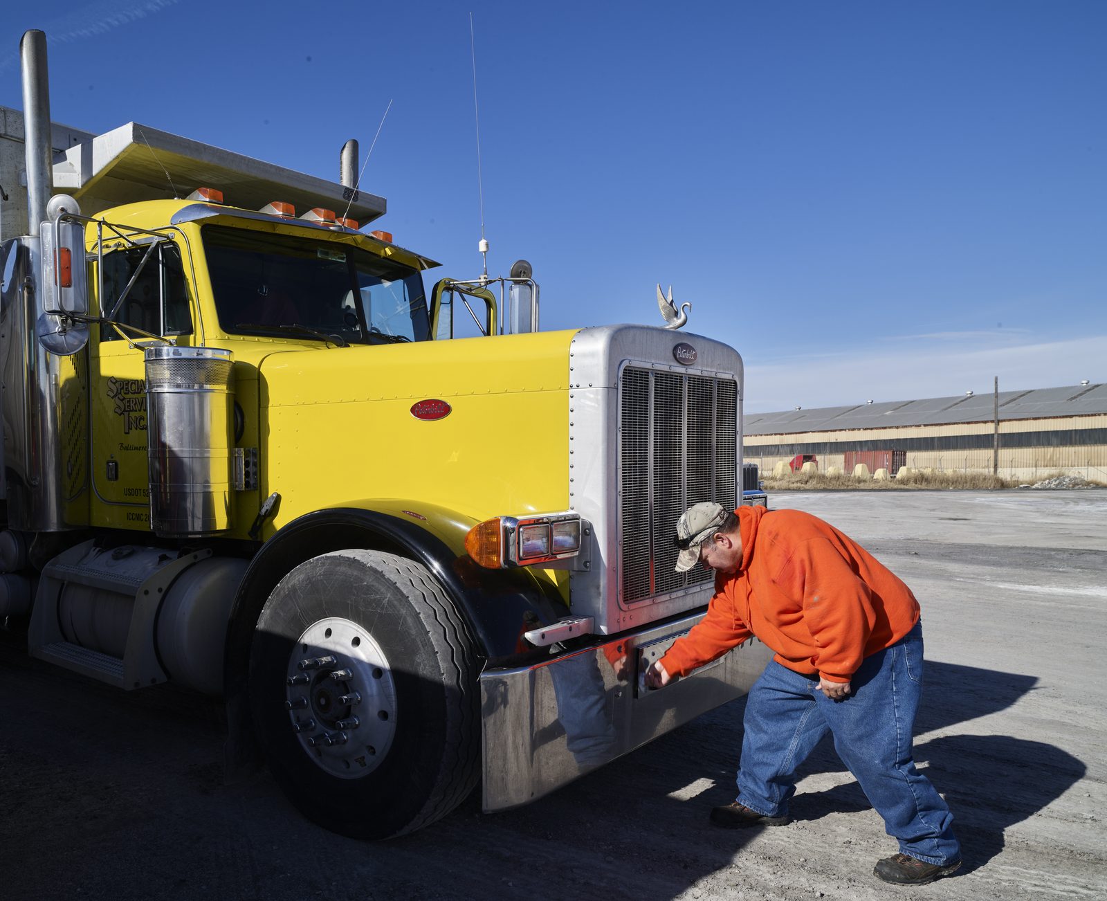 A driver checks the front of his truck before a trip